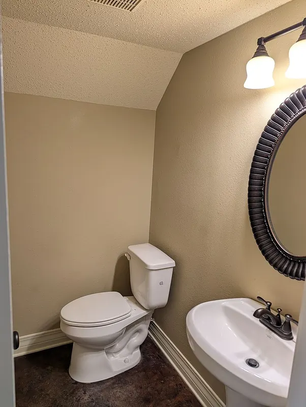 Downstairs half bath with pedestal sink and oval mirror